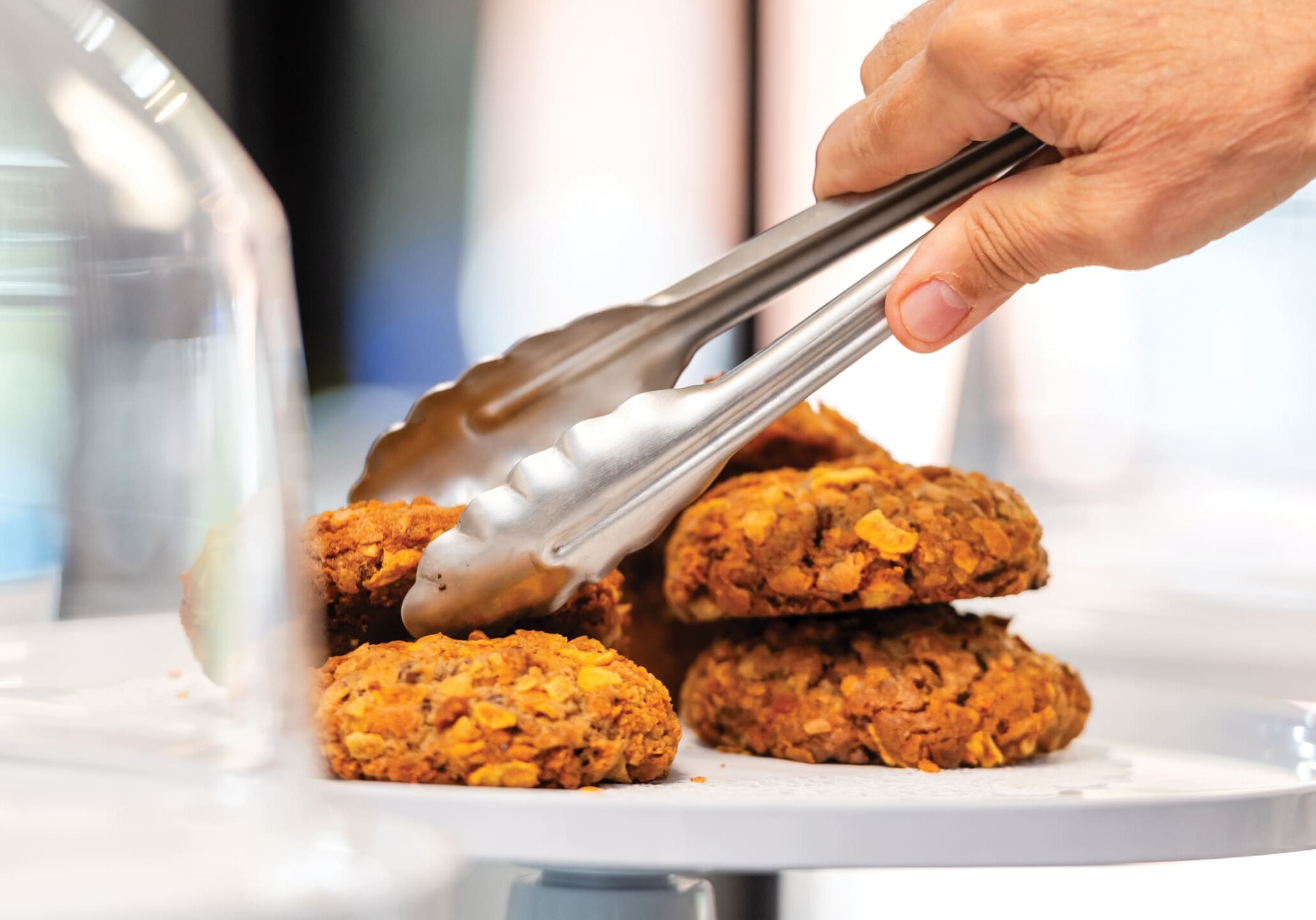 Hand using tongs to serve cookies.